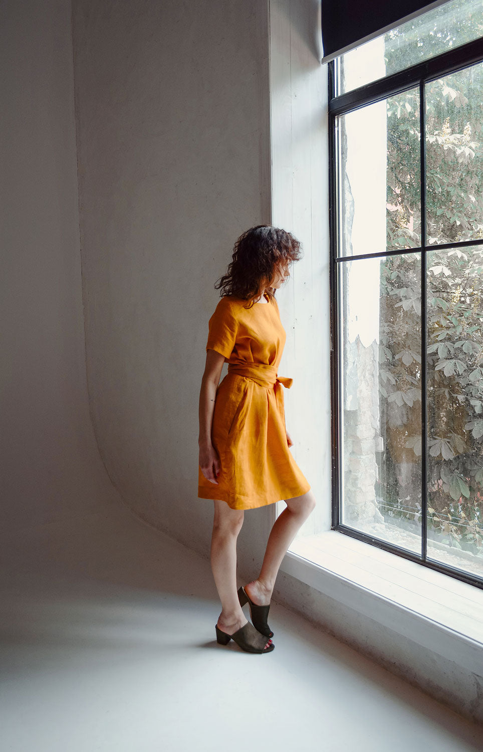 a woman in a yellow dress looking out a window